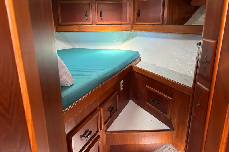  Yacht Photos Pics 1985 Egg Harbor 37 Tournament cabin with wooden cabinetry and teal bedding.