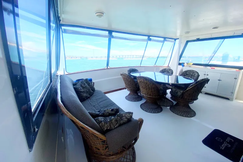 Sea Sharp Yacht Photos Pics Spacious interior of 1990 Viking 63 Motor Yacht with wicker furniture and ocean view.