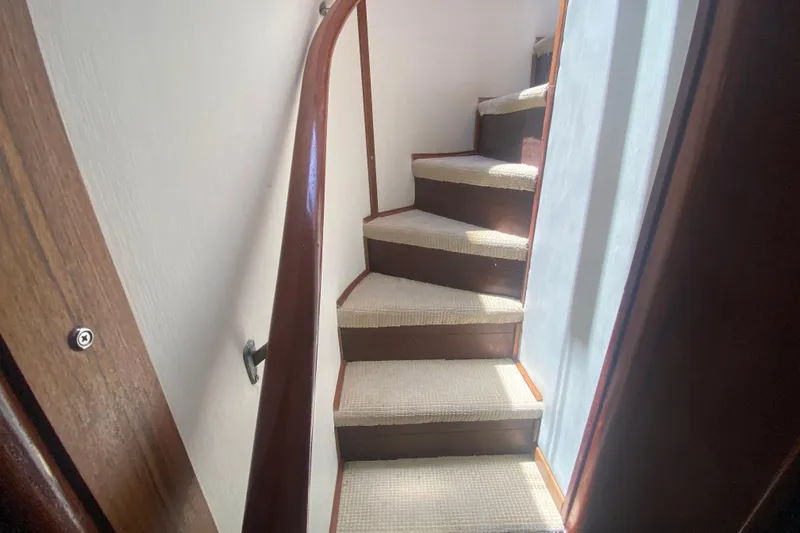 Sea Sharp Yacht Photos Pics Carpeted stairs inside a 1990 Viking 63 Motor Yacht, featuring wooden handrails.