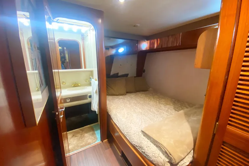 Sea Sharp Yacht Photos Pics Cozy bedroom and bathroom in 1990 Viking 63 Motor Yacht, featuring wood accents and soft lighting.