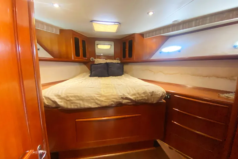 Sea Sharp Yacht Photos Pics Cozy bedroom in 1990 Viking 63 Motor Yacht with wood paneling and built-in storage.