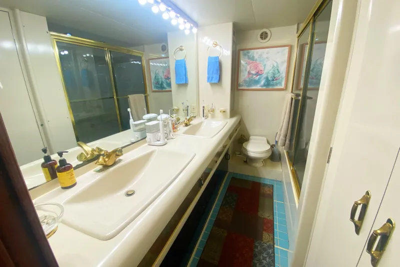 Sea Sharp Yacht Photos Pics Luxurious bathroom in a 1990 Viking 63 Motor Yacht with double sinks and gold accents.