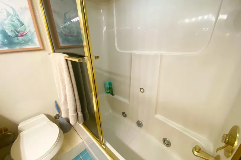 Sea Sharp Yacht Photos Pics Bathroom in 1990 Viking 63 Motor Yacht with shower, toilet, and gold accents.