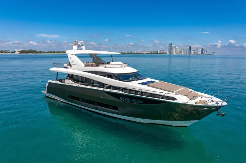 Oceana Yacht Photos Pics Luxurious 2015 Prestige 750 yacht cruising on clear blue waters near a city skyline.