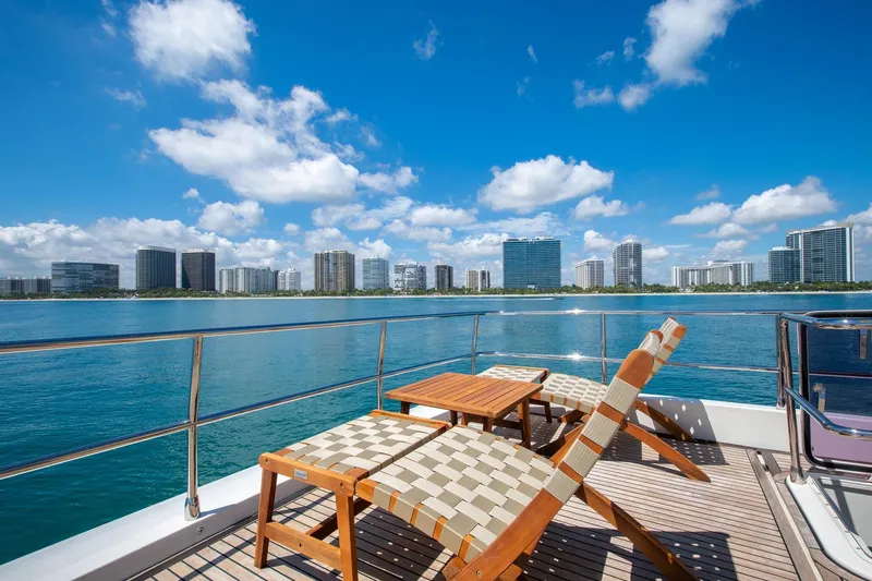 Oceana Yacht Photos Pics Luxury yacht deck with lounge chairs, table, and city skyline view under blue sky. Prestige 750, 2015.