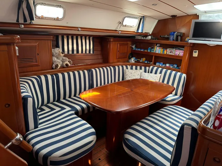  Yacht Photos Pics Interior of 2004 Beneteau 50 yacht with striped seating and wooden table.
