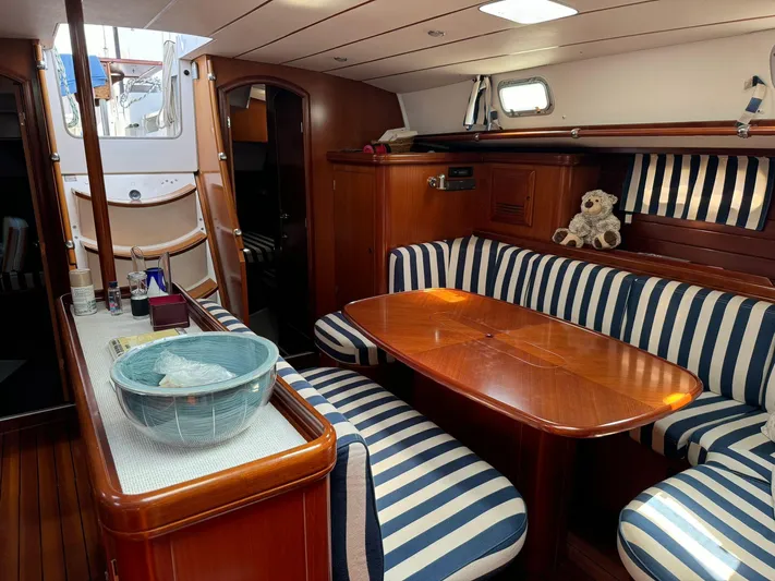  Yacht Photos Pics Interior of 2004 Beneteau 50 yacht with striped seating and wooden table.