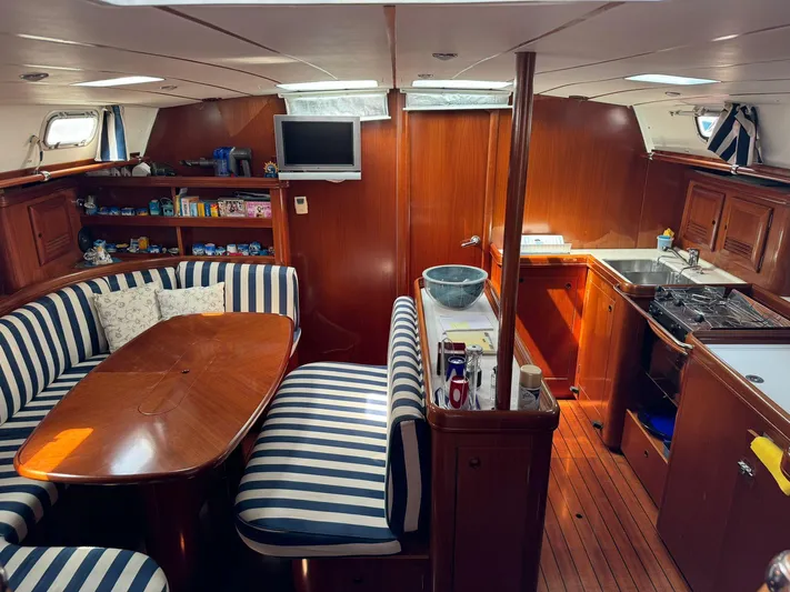  Yacht Photos Pics Interior of 2004 Beneteau 50 yacht with striped seating, wooden table, and kitchen area.