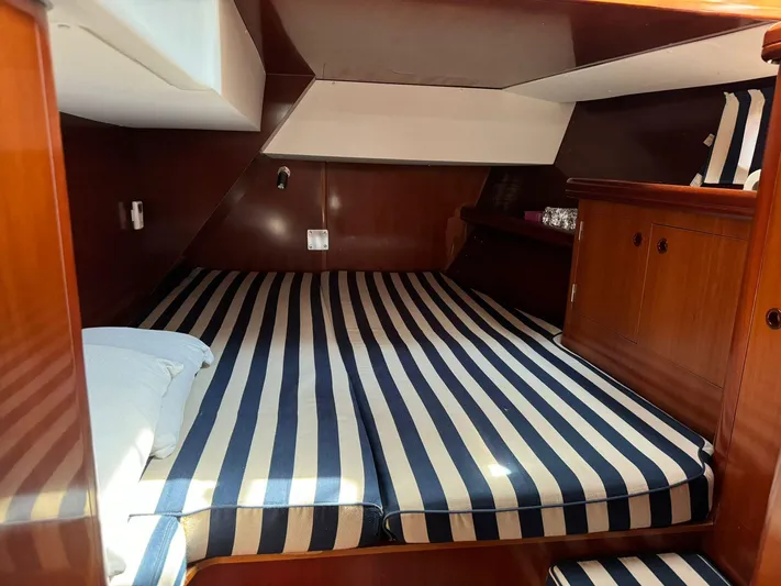  Yacht Photos Pics 2004 Beneteau 50 yacht cabin with striped bedding and wooden interior.