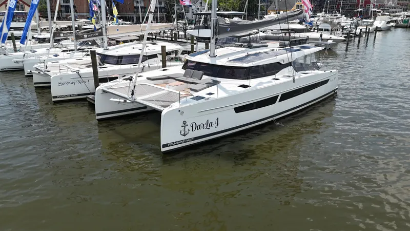 Darla Jay Yacht Photos Pics 2023 Fountaine Pajot Aura 51 catamaran docked in a marina, surrounded by other boats.