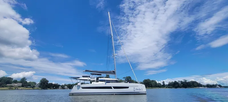 Darla Jay Yacht Photos Pics 2023 Fountaine Pajot Aura 51 catamaran sailing on a calm, scenic waterway.