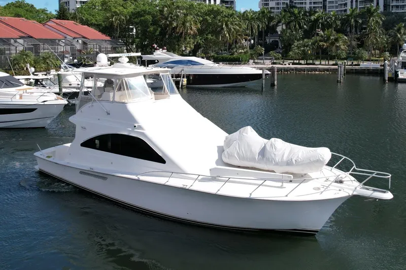 Etan Yacht Photos Pics 2005 Ocean Yachts 50 Super Sport in marina, surrounded by lush greenery and other boats.