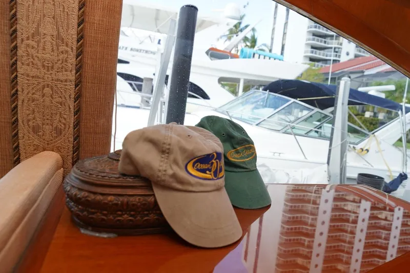 Etan Yacht Photos Pics Two Ocean Yachts caps on a wooden surface, with yachts visible outside the window.