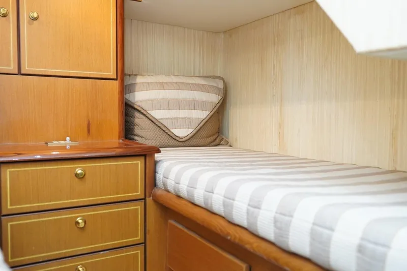 Etan Yacht Photos Pics 2005 Ocean Yachts 50 Super Sport cabin with striped bedding and wooden cabinetry.