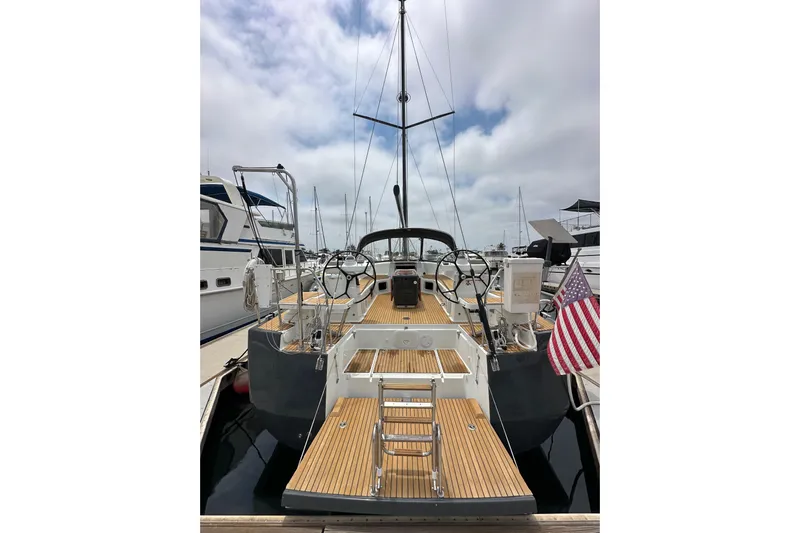  Yacht Photos Pics 2018 Jeanneau 54 yacht with wooden deck, docked at marina, featuring dual steering wheels.
