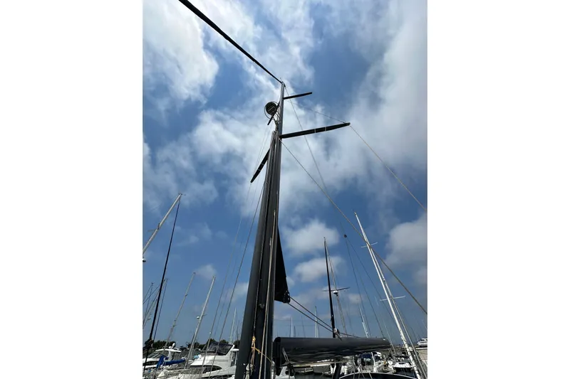  Yacht Photos Pics 2018 Jeanneau 54 sailboat mast against a cloudy blue sky in a marina.
