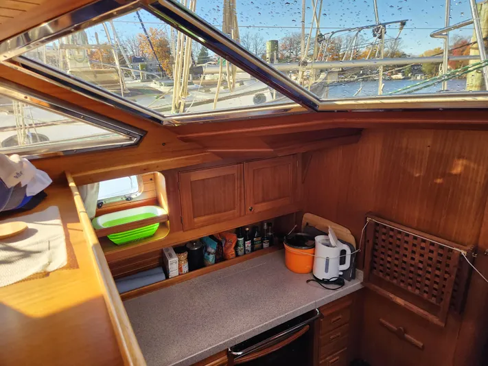Lizette Yacht Photos Pics Cozy galley inside a 2000 Regina 43 sailboat, featuring wooden cabinetry and a countertop.