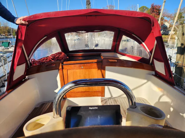 Lizette Yacht Photos Pics Cockpit of a 2000 Regina 43 sailboat with red canopy and wooden accents.