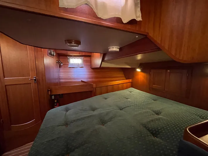 Lizette Yacht Photos Pics Cozy cabin interior of 2000 Regina 43 yacht with wooden finish and green bedding.