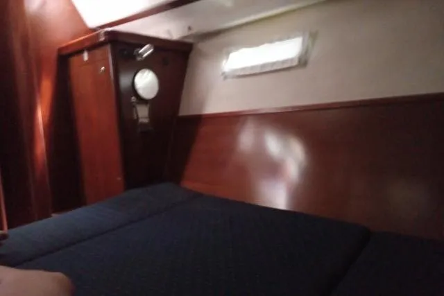 Pacifico Yacht Photos Pics Interior cabin of 2005 Beneteau 393 yacht with wooden paneling and porthole.