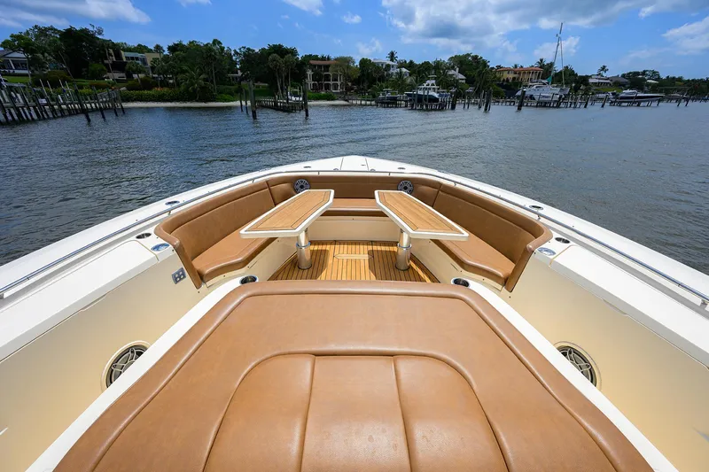 53 Scout Yacht Photos Pics 2021 Scout 530 LXF boat with luxurious seating and tables on a serene waterfront.