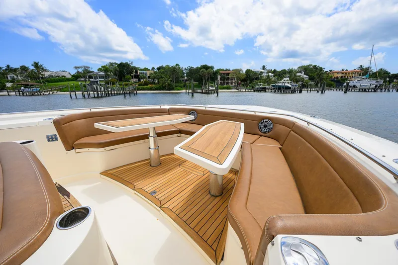 53 Scout Yacht Photos Pics 2021 Scout 530 LXF boat with luxurious seating and tables, docked by a scenic waterfront.