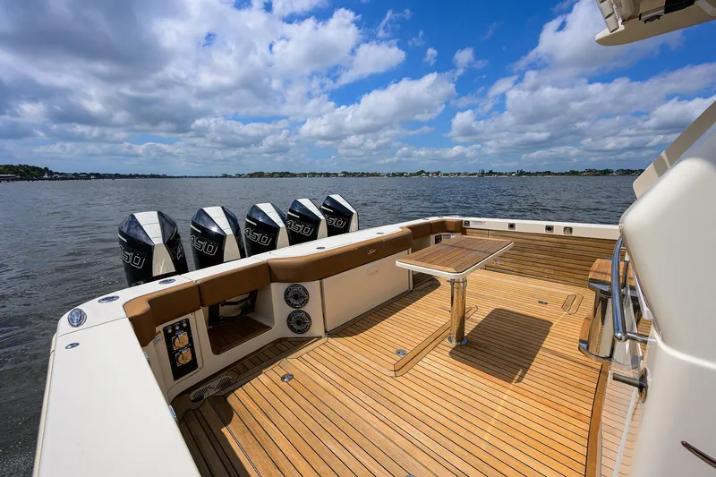 53 Scout Yacht Photos Pics 2021 Scout 530 LXF boat deck with multiple engines, wooden flooring, and table on a sunny day.