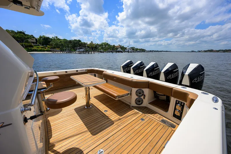 53 Scout Yacht Photos Pics 2021 Scout 530 LXF boat deck with seating, table, and multiple outboard engines on a sunny day.