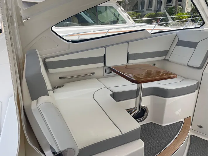  Yacht Photos Pics 2023 Pursuit DC 365 Dual Console interior with white seating and wooden table.