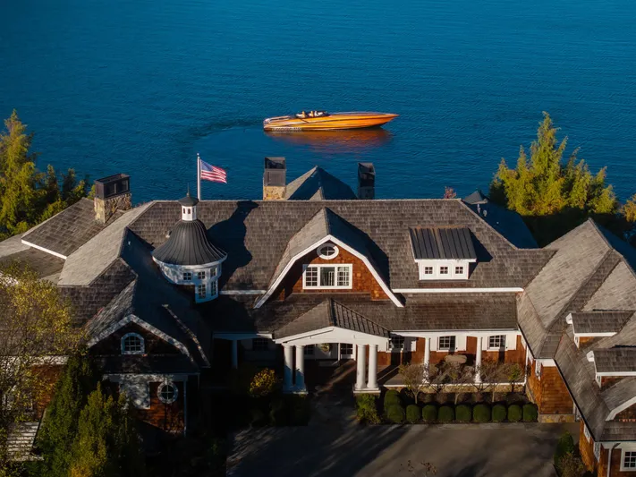  Yacht Photos Pics Aerial view of a luxury lakeside home with a 2020 Fountain 47 Lightning boat on the water.