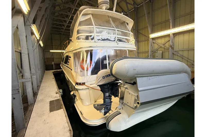 Bellissimo Yacht Photos Pics 2006 Silverton 38 Sport Bridge yacht docked in a covered marina with inflatable boat.