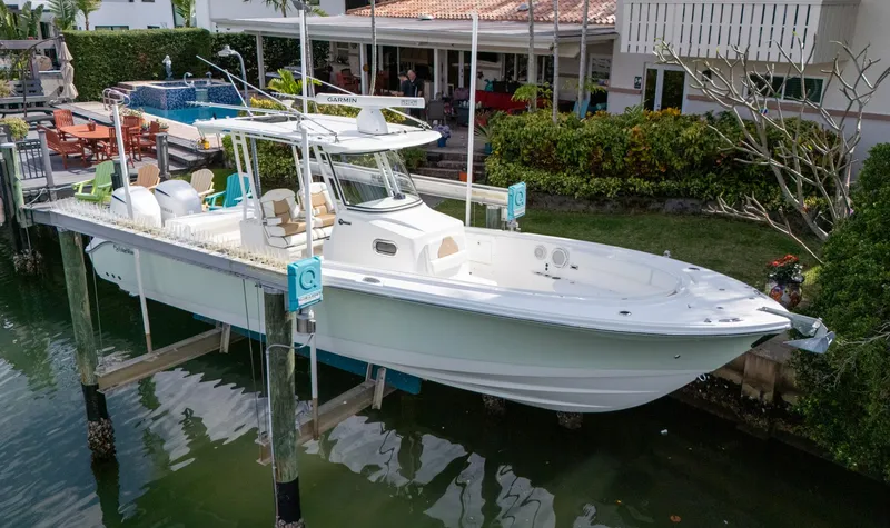 Dan's Seachelle Yacht Photos Pics 2019 Edgewater 320CC boat docked near a waterfront home.
