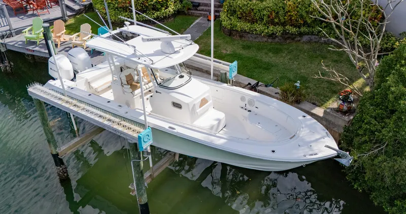 Dan's Seachelle Yacht Photos Pics 2019 Edgewater 320CC boat docked on a lift, surrounded by greenery.
