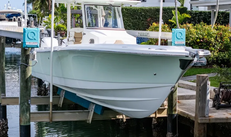 Dan's Seachelle Yacht Photos Pics 2019 Edgewater 320CC boat docked on lift, surrounded by lush greenery.
