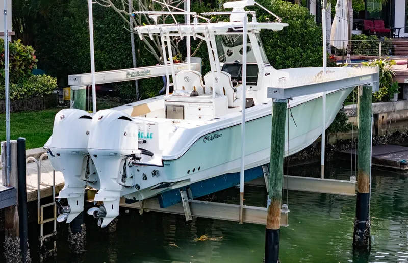 Dan's Seachelle Yacht Photos Pics 2019 Edgewater 320CC boat on lift, dual engines, docked by waterfront property.