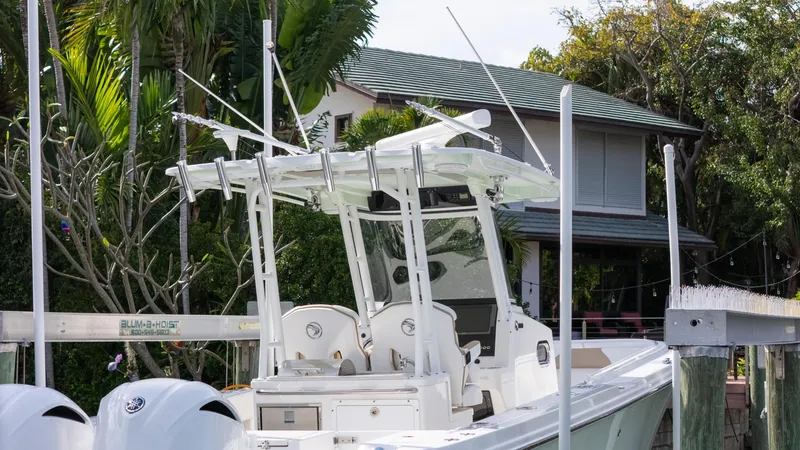 Dan's Seachelle Yacht Photos Pics 2019 Edgewater 320CC boat docked near a house with lush greenery.