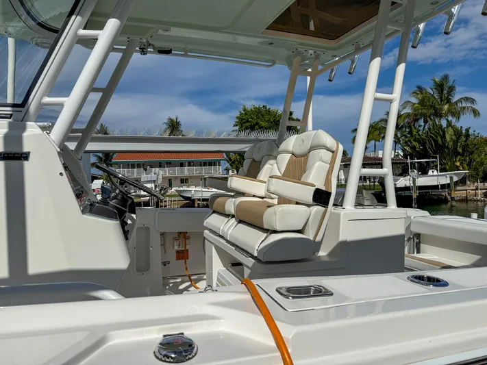 Dan's Seachelle Yacht Photos Pics 2019 Edgewater 320CC boat interior with cushioned seating and helm, docked near palm trees.