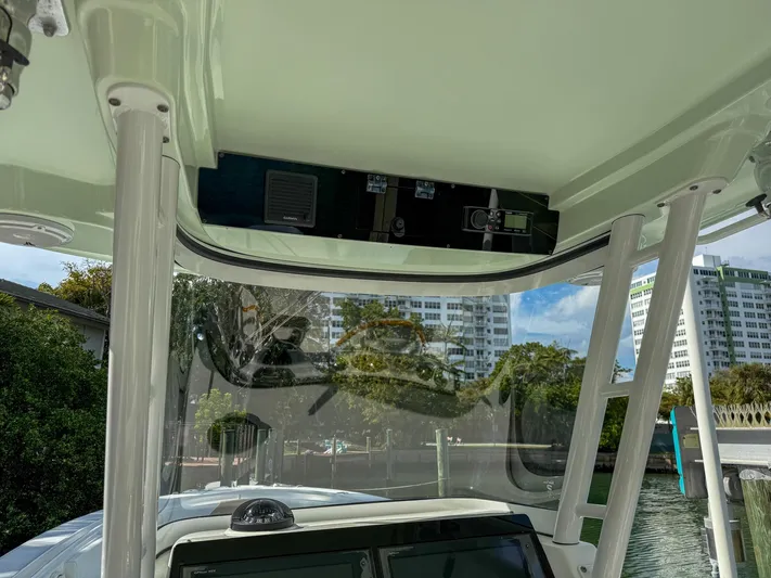 Dan's Seachelle Yacht Photos Pics 2019 Edgewater 320CC boat console with overhead electronics, docked near waterfront buildings.