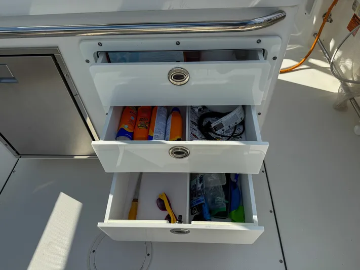 Dan's Seachelle Yacht Photos Pics Open storage drawers on a 2019 Edgewater 320CC boat, containing various items.
