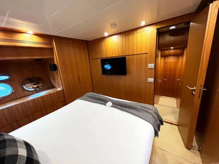 Koko Yacht Photos Pics Luxurious bedroom on 2006 Sanlorenzo SL72 yacht with wood paneling and porthole windows.