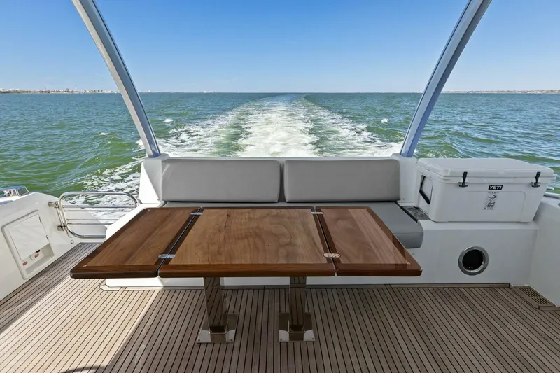 Radiant Yacht Photos Pics Prestige 630 Flybridge 2019 yacht with wooden table, ocean view, and seating area.