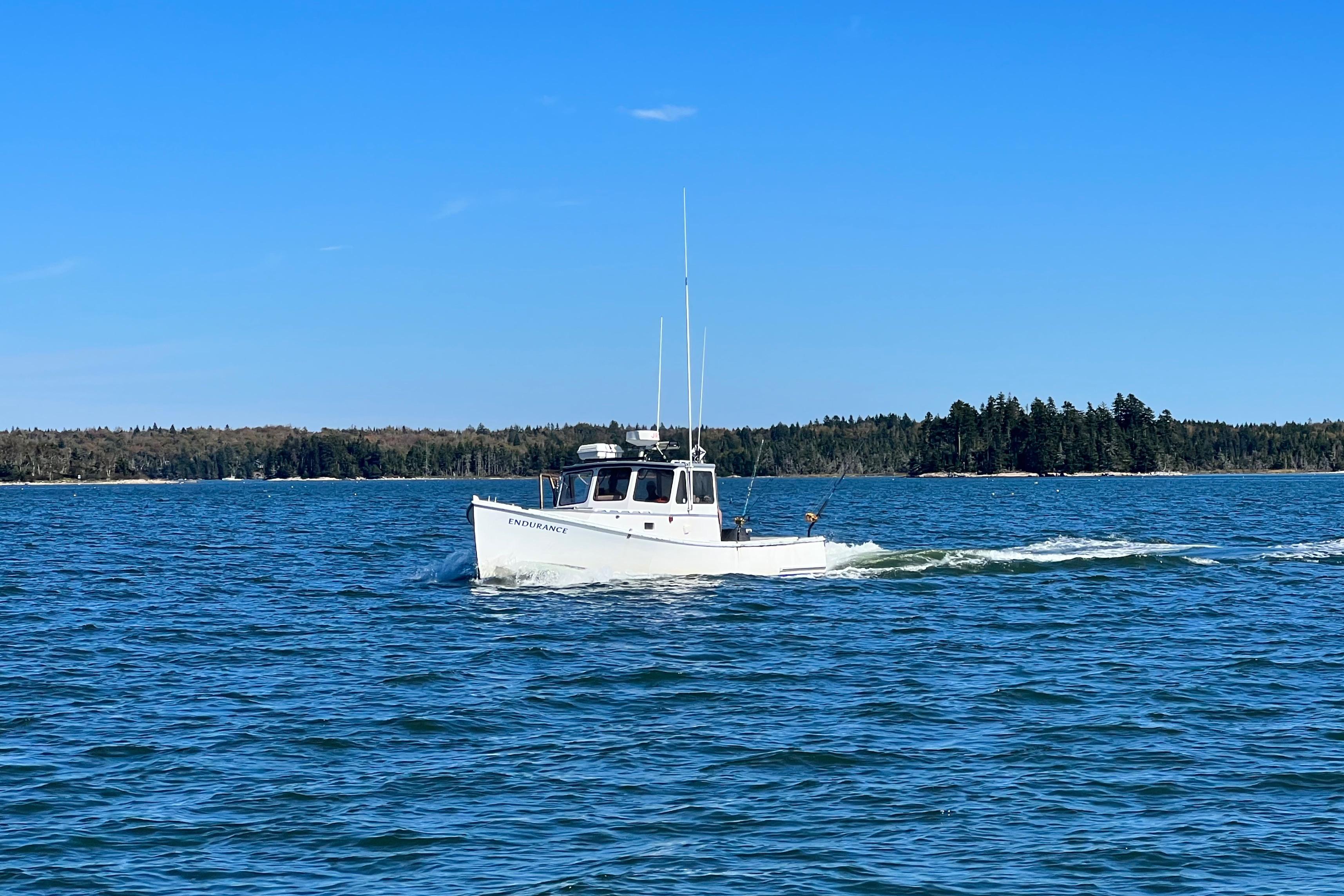 1980 Holland 32 boat cruising on a calm blue sea under a clear sky.