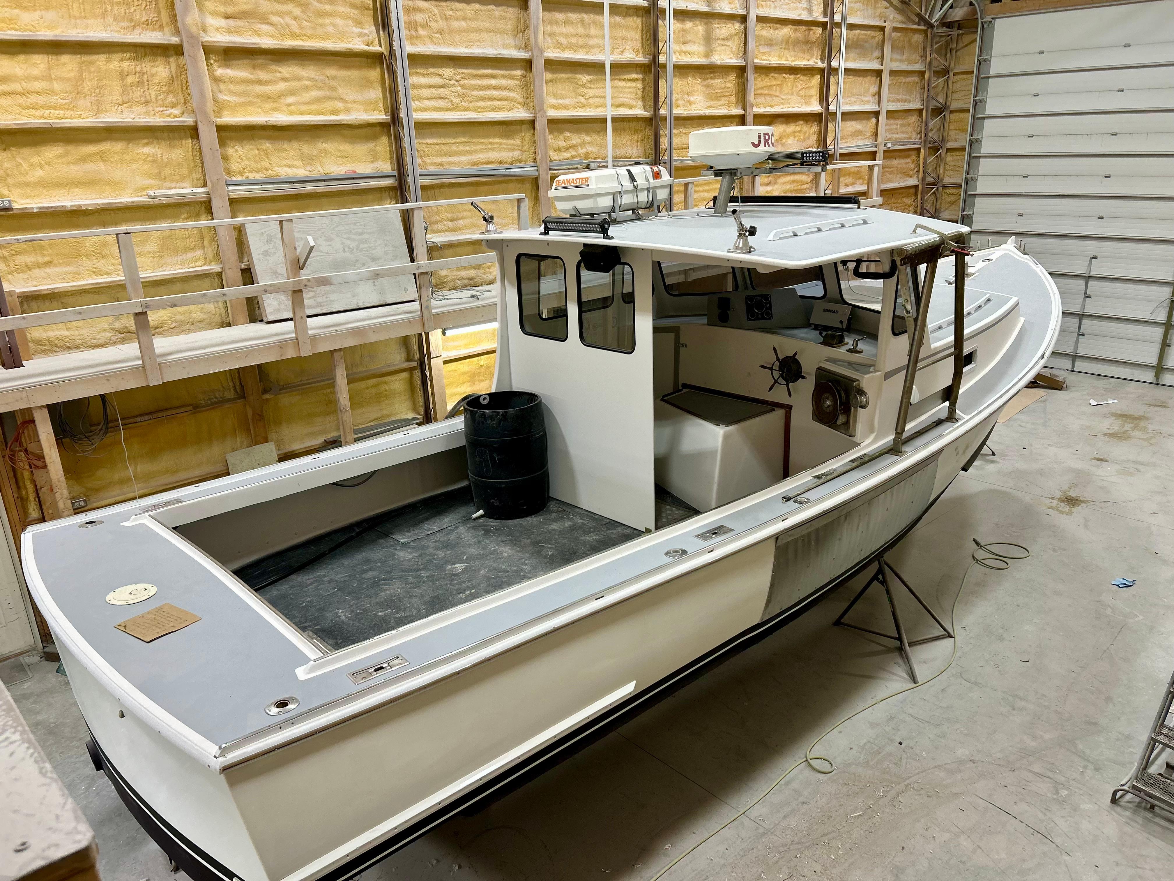 1980 Holland 32 boat in a workshop, featuring a spacious deck and enclosed cabin.
