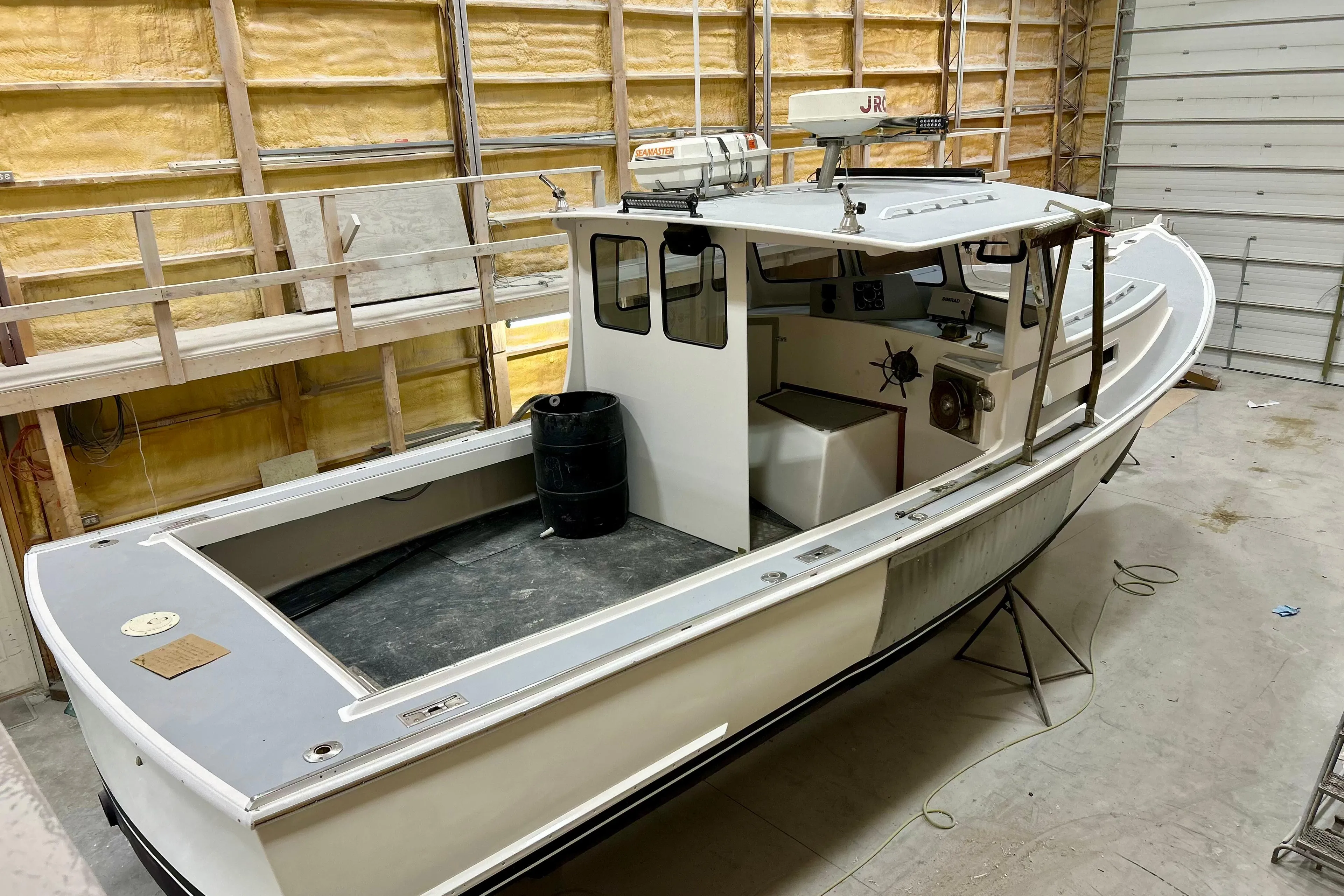 1980 Holland 32 boat in a workshop, featuring a spacious deck and enclosed cabin.