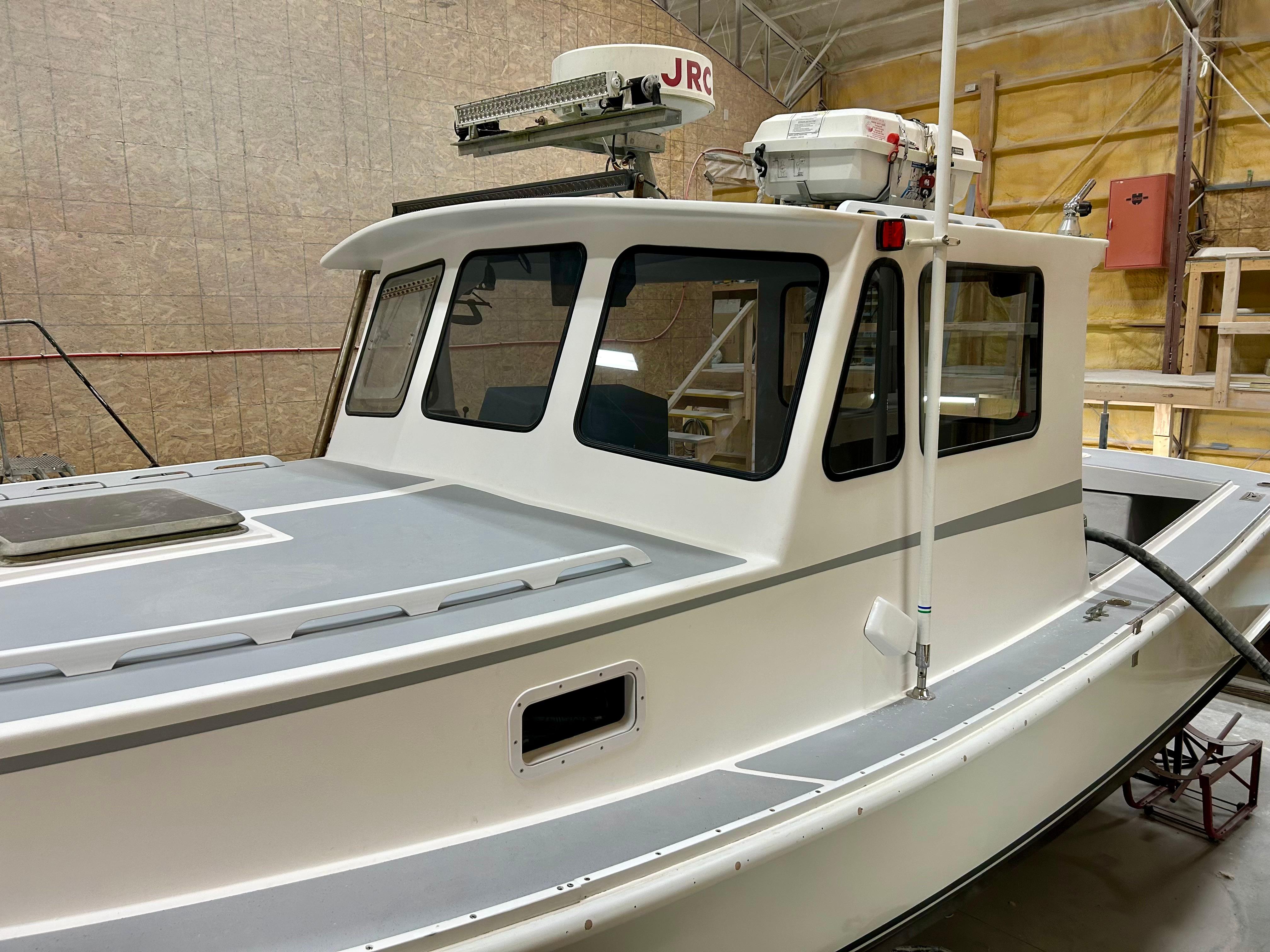 1980 Holland 32 boat with white cabin and advanced navigation equipment in a workshop.