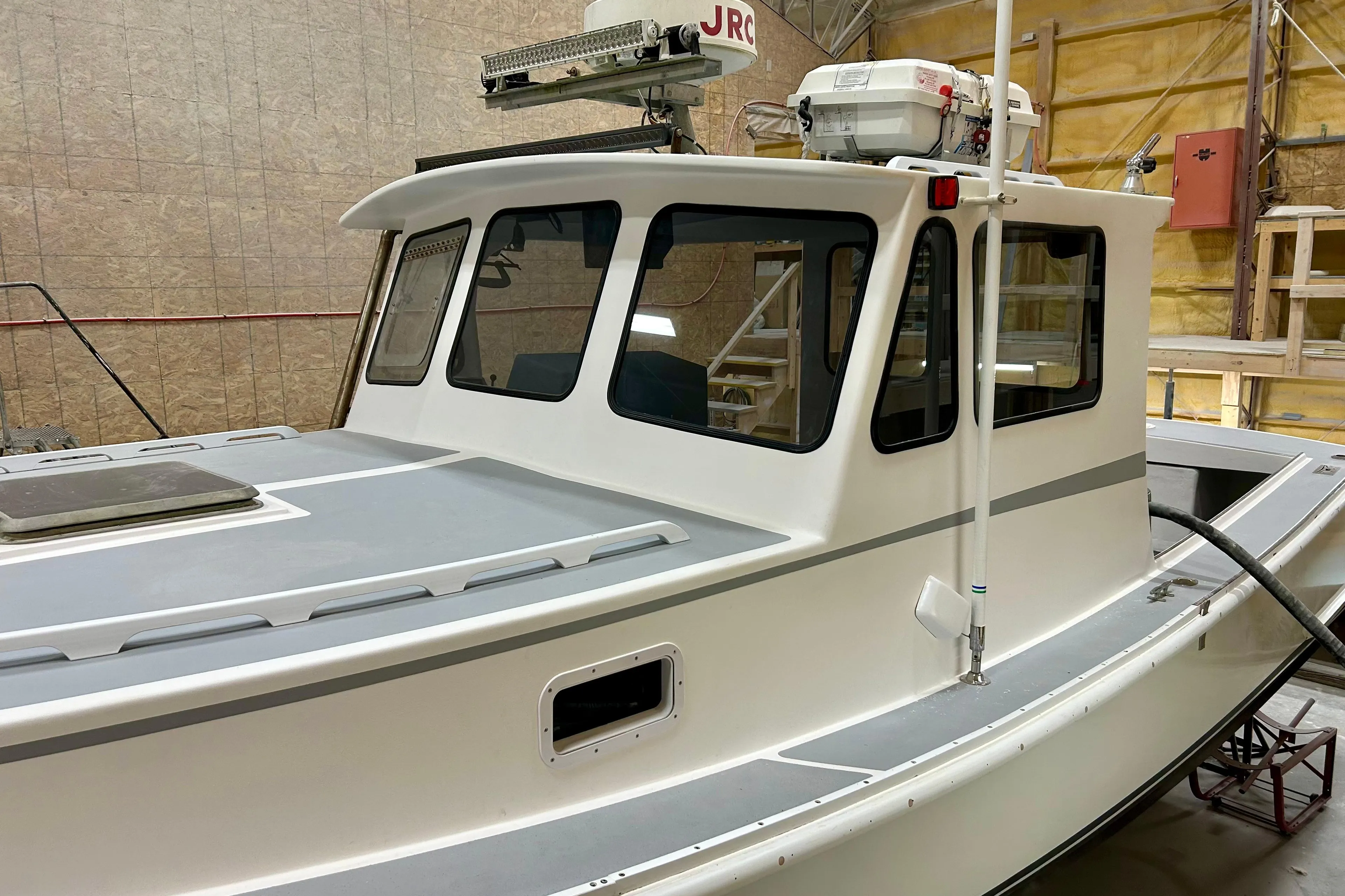 1980 Holland 32 boat with white cabin and advanced navigation equipment in a workshop.