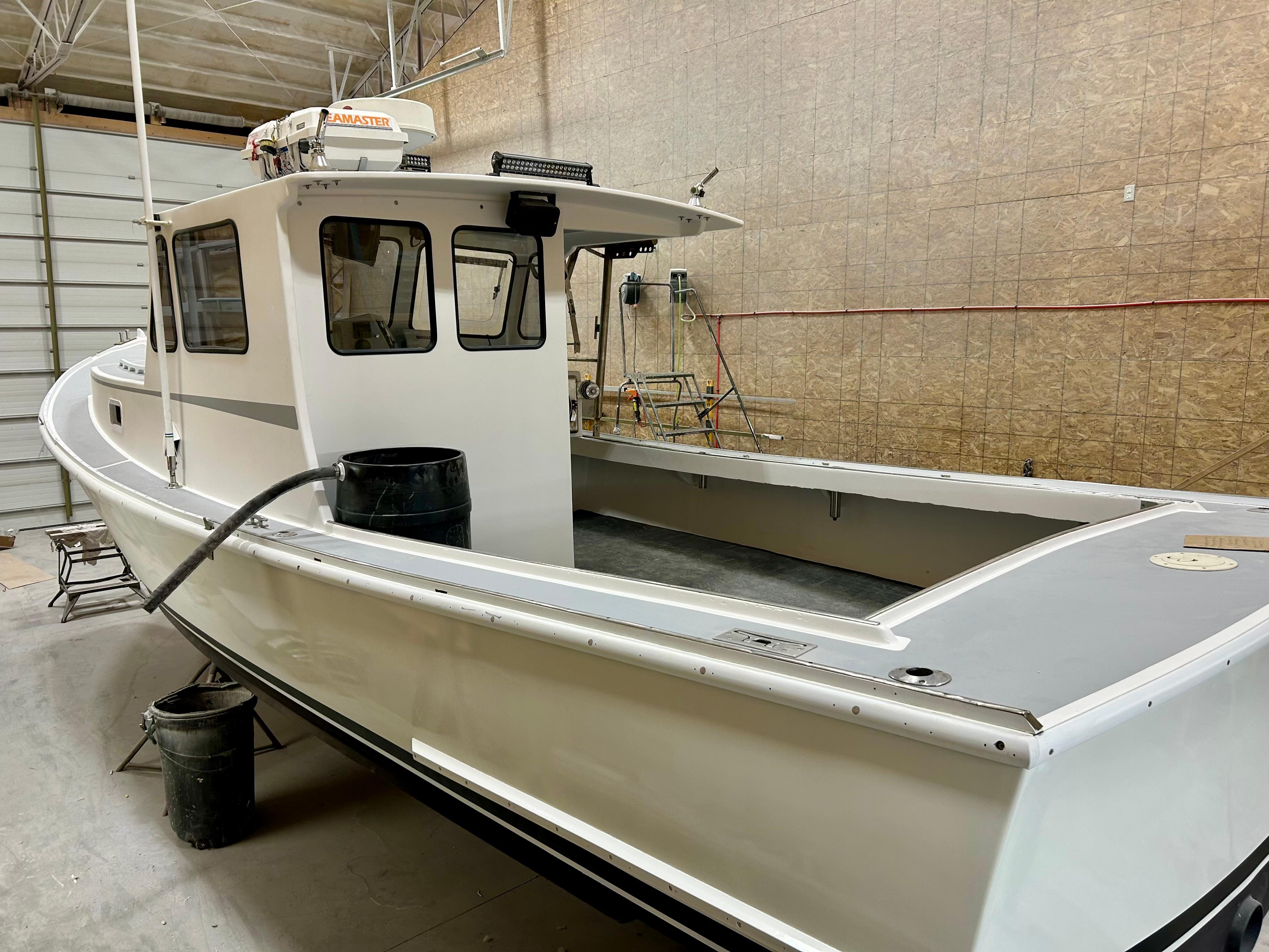 1980 Holland 32 boat in a workshop, white exterior, spacious deck, enclosed cabin.