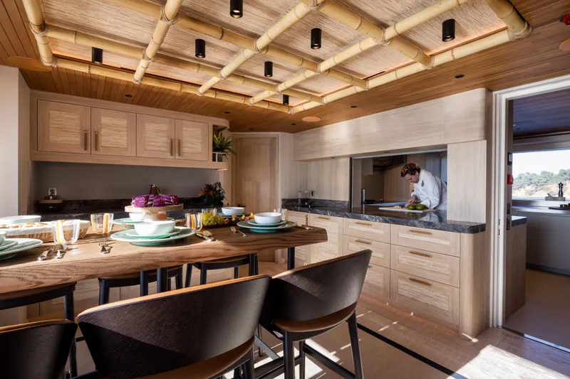 King Benji Yacht Photos Pics Luxurious kitchen interior on 2024 Dunya Yachts, featuring elegant wood finishes and modern dining setup.