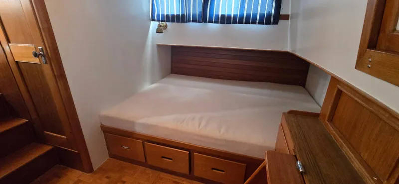 Interlude Yacht Photos Pics 1987 Grand Banks 36 Classic cabin interior with bed, wooden drawers, and striped curtains.