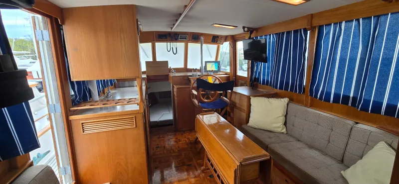 Interlude Yacht Photos Pics Interior of 1987 Grand Banks 36 Classic yacht with wood finish and blue-striped curtains.
